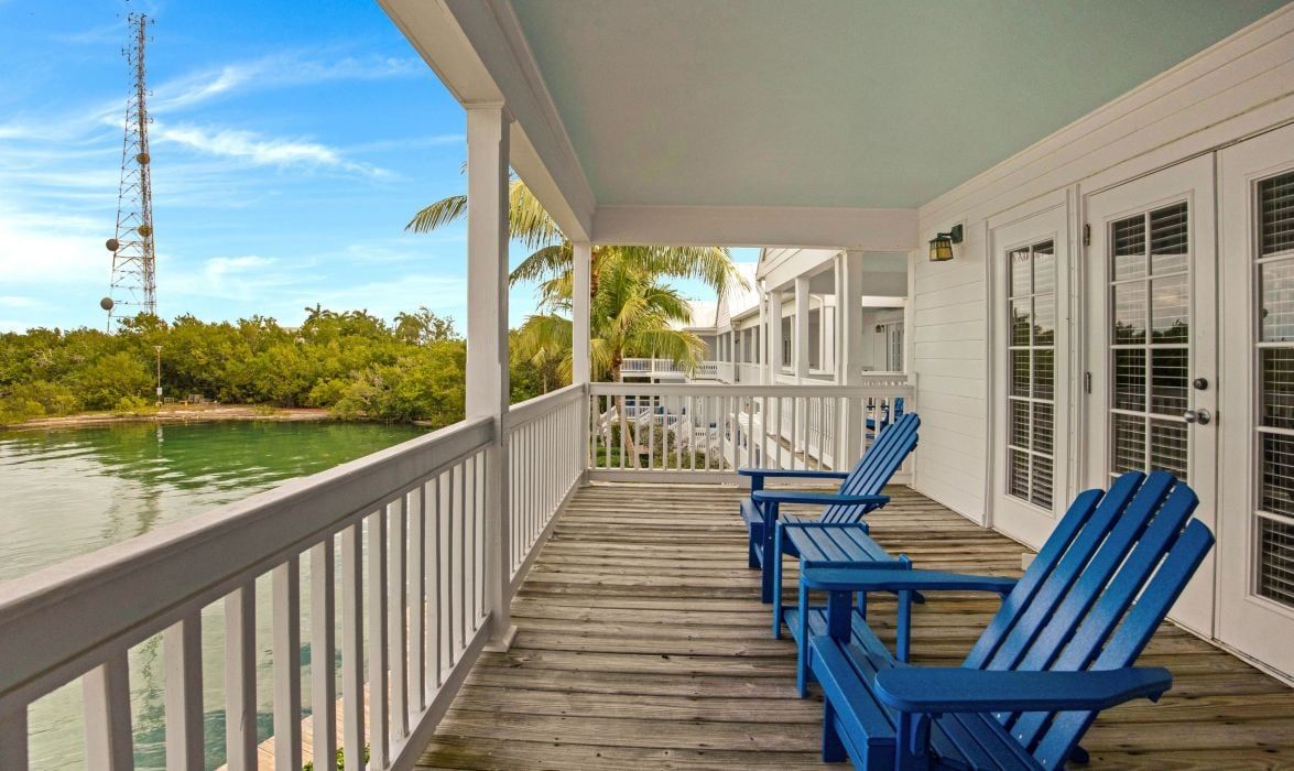 image Covered porch with blue adirondack chairs overlooking a canal boardwalk