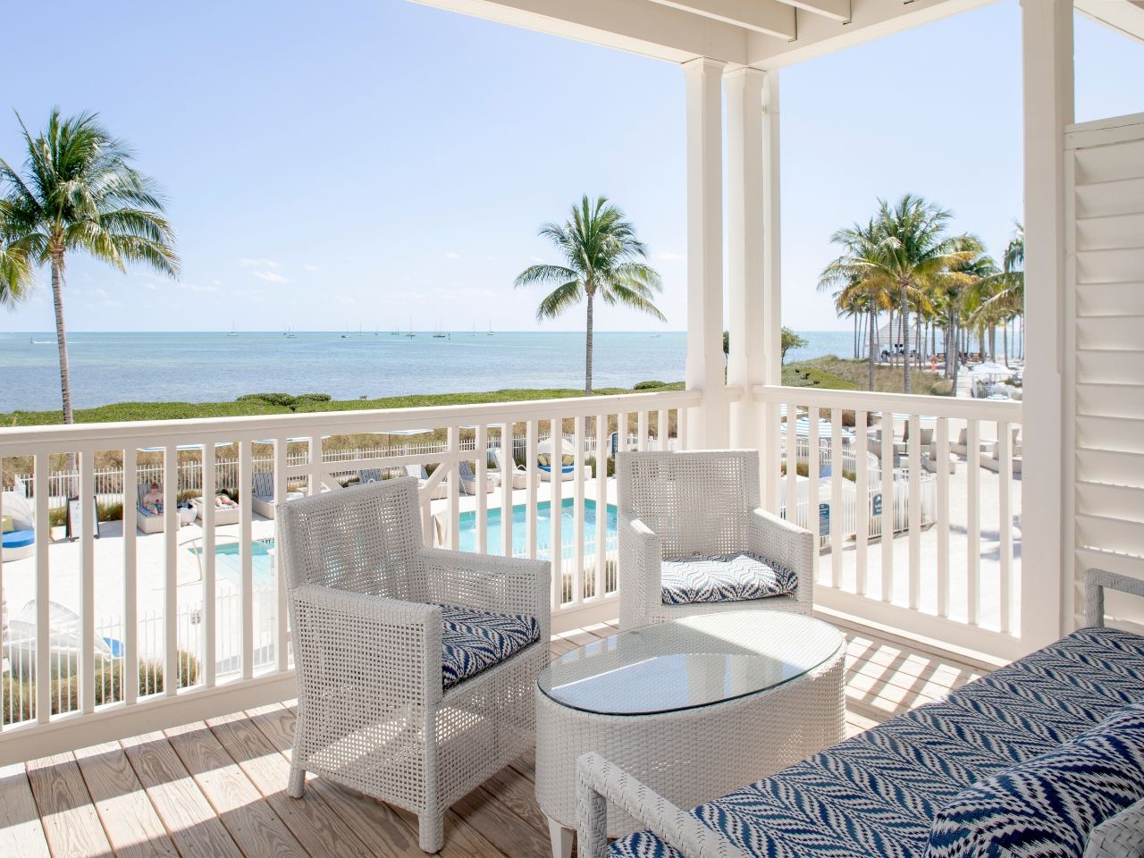 image Relaxing balcony space with cozy seating and panoramic views of palm trees and the ocean.
