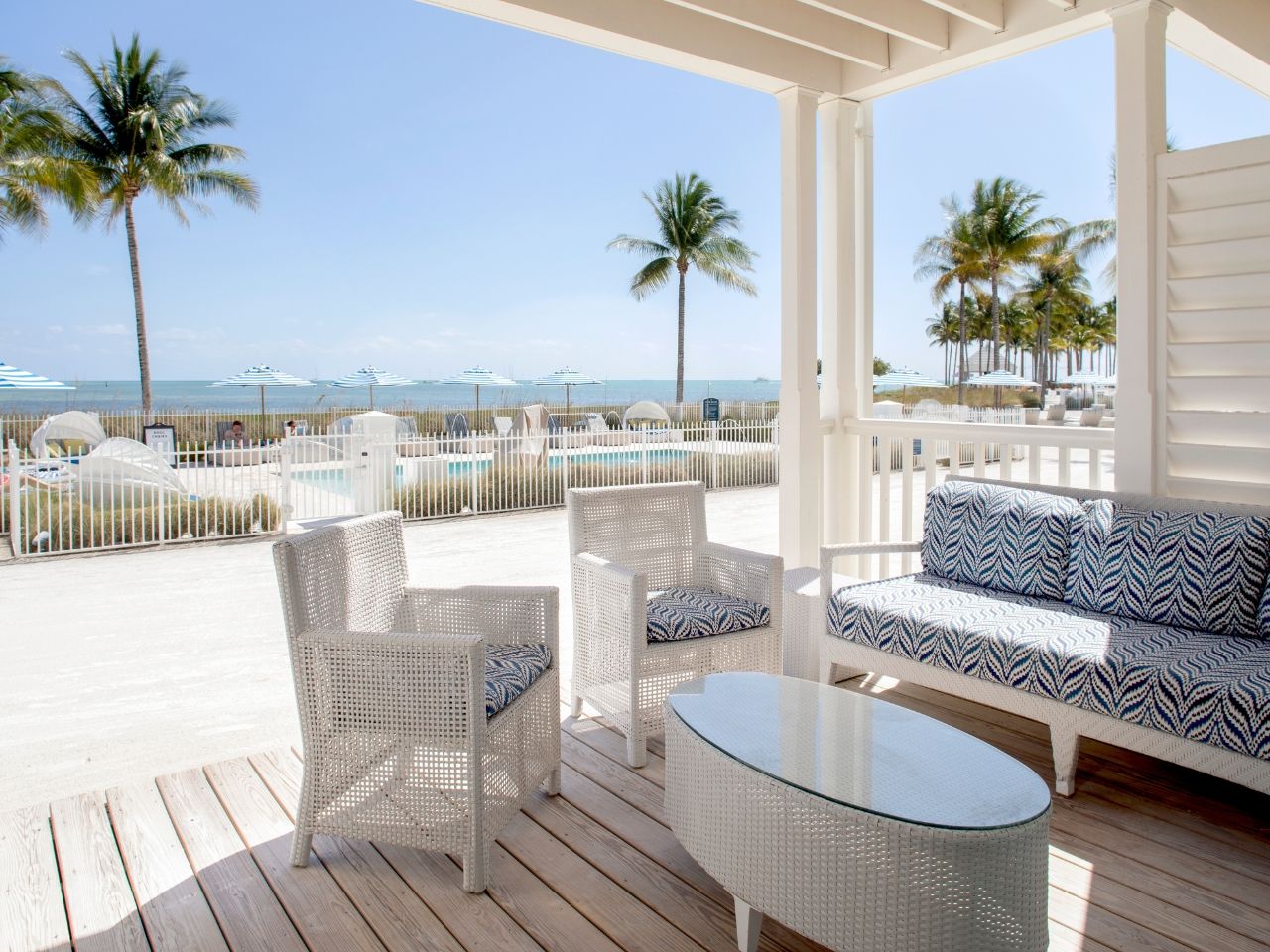 image Cozy beachfront patio with elegant seating, offering breathtaking views of the ocean and swaying palms.