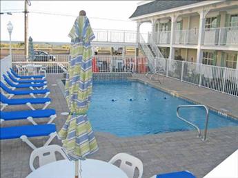 image Sparkling heated pool with plenty of lounge chairs—perfect for relaxing and soaking up the sun.