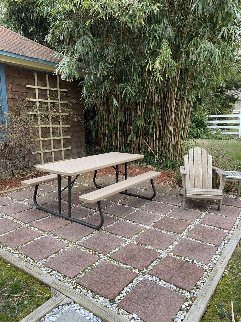 image Serene backyard patio with a picnic table and Adirondack chair, perfect for outdoor dining or relaxing by the rose garden.