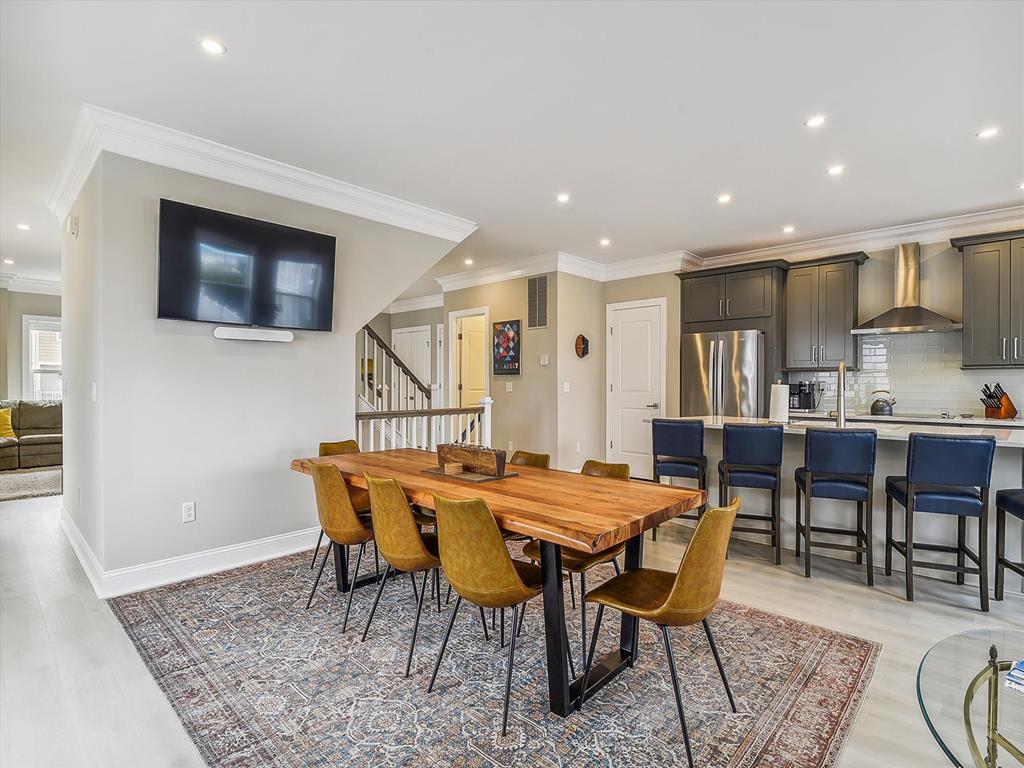 image Open-concept dining and kitchen area, featuring a mounted TV for a relaxed dining experience.