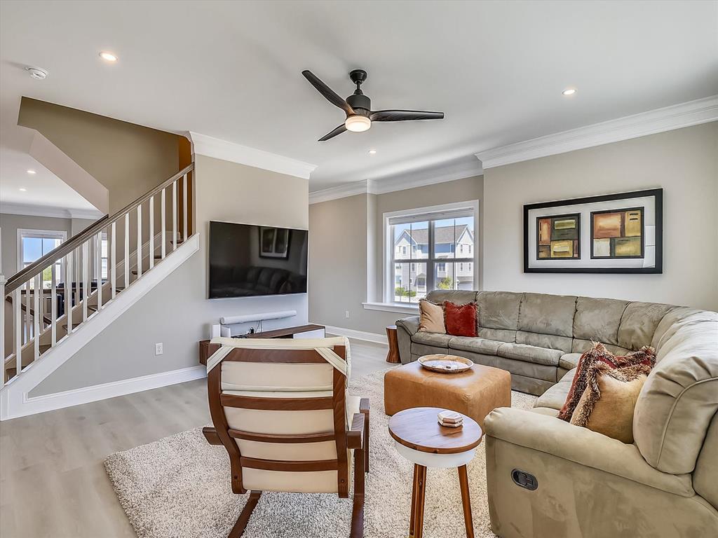 image Comfortable and airy living room with plush seating, a ceiling fan, and an inviting layout perfect for relaxation.