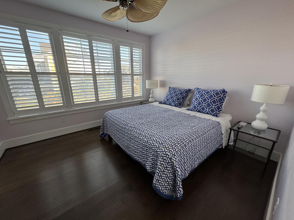 image Elegant bedroom with rich wooden floors, cozy bedding, and plantation shutters for added privacy.