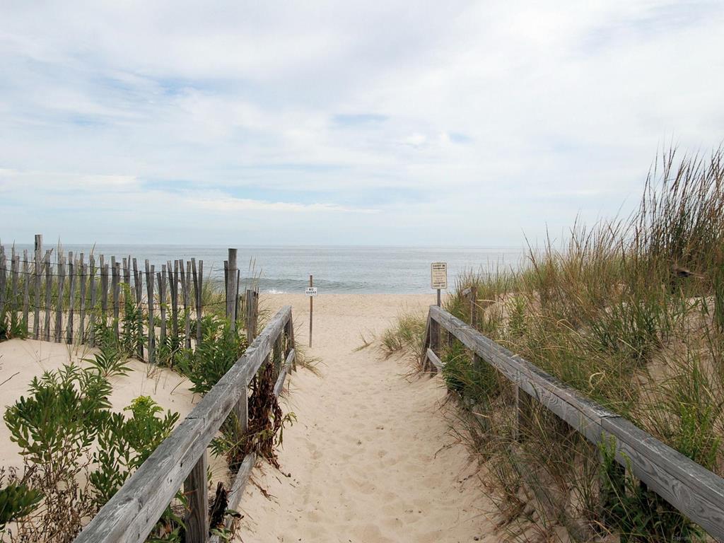 image Scenic beach entrance with wooden pathways through the dunes, just steps from the home.