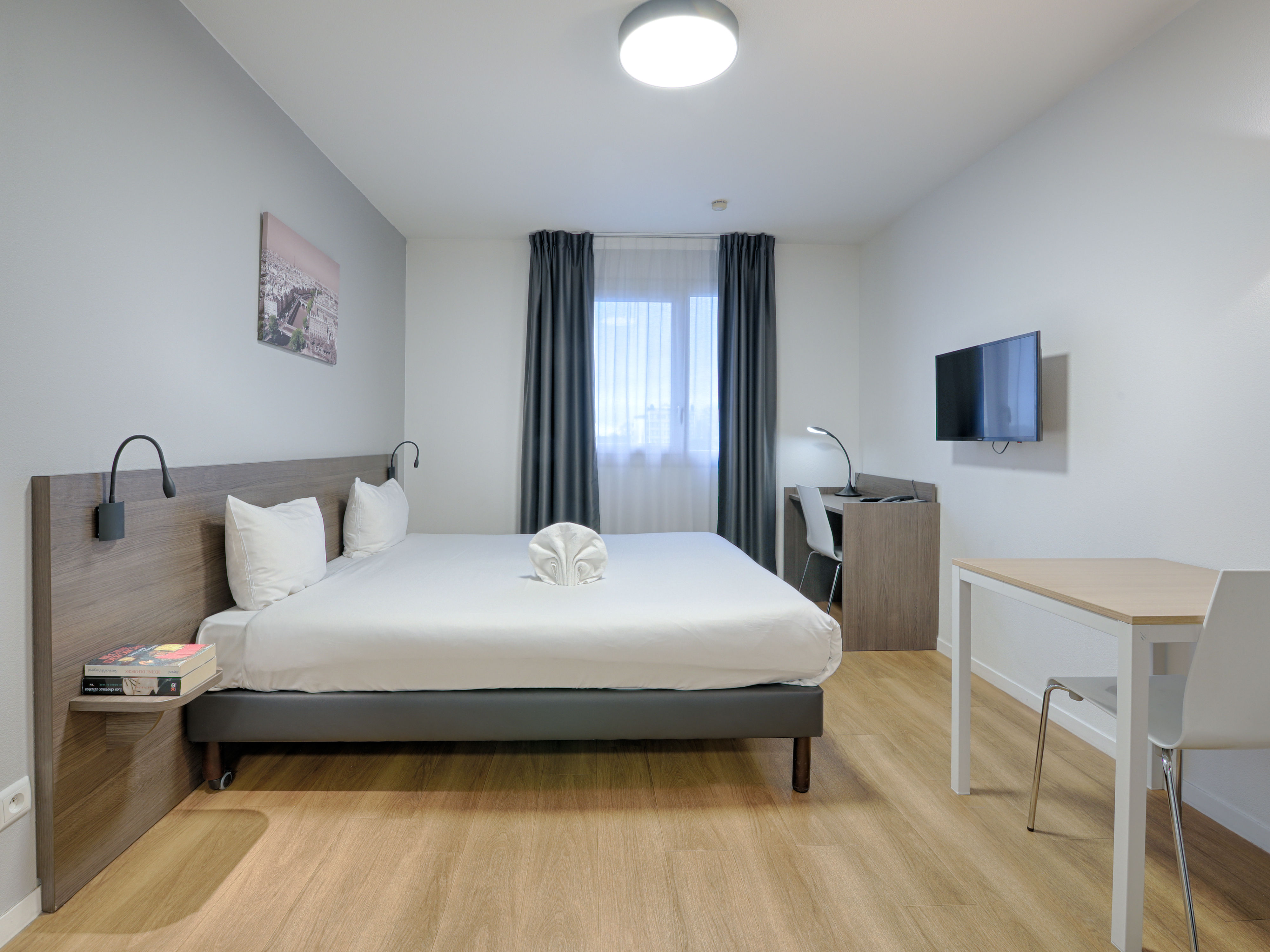 image Spacious studio featuring a double bed, flat-screen TV, and work desk, perfect for relaxation or productivity.
