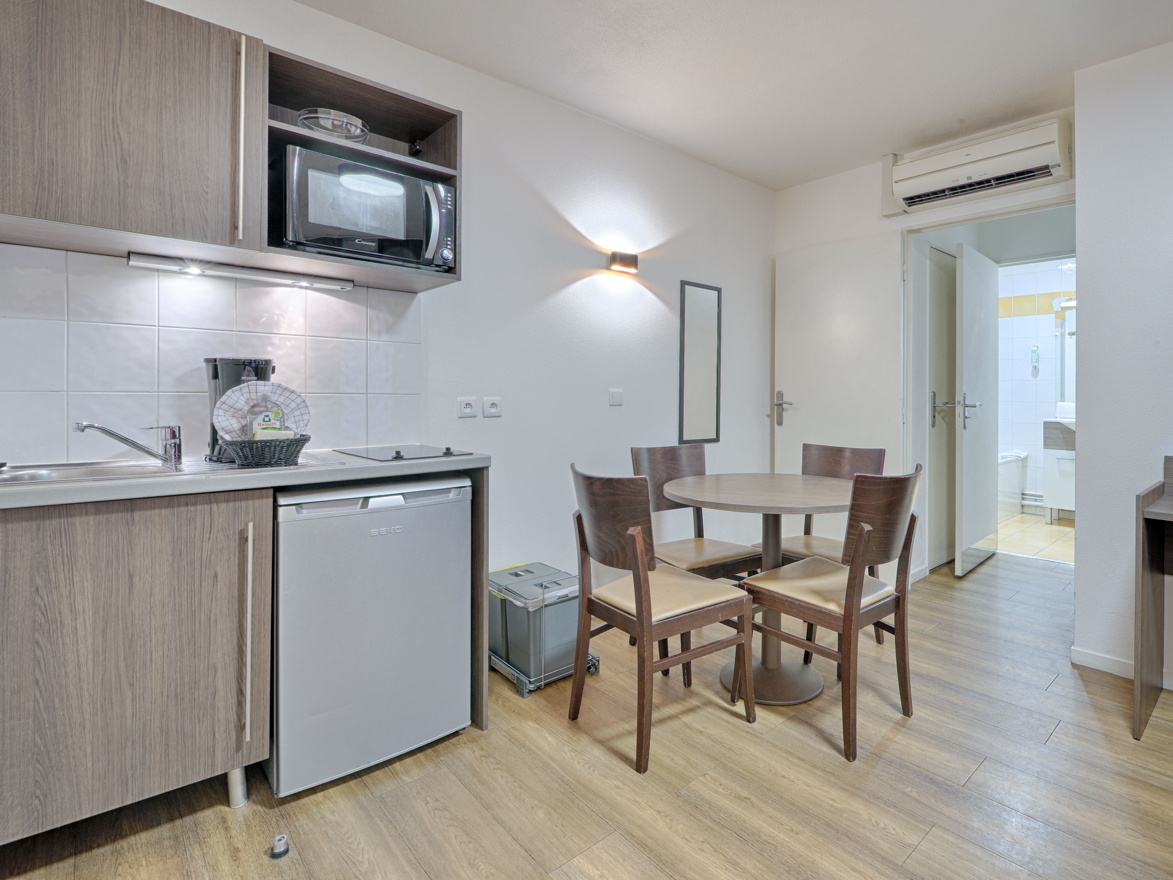 image Modern kitchenette with electric hob, microwave, and dining area, perfect for preparing and enjoying meals.