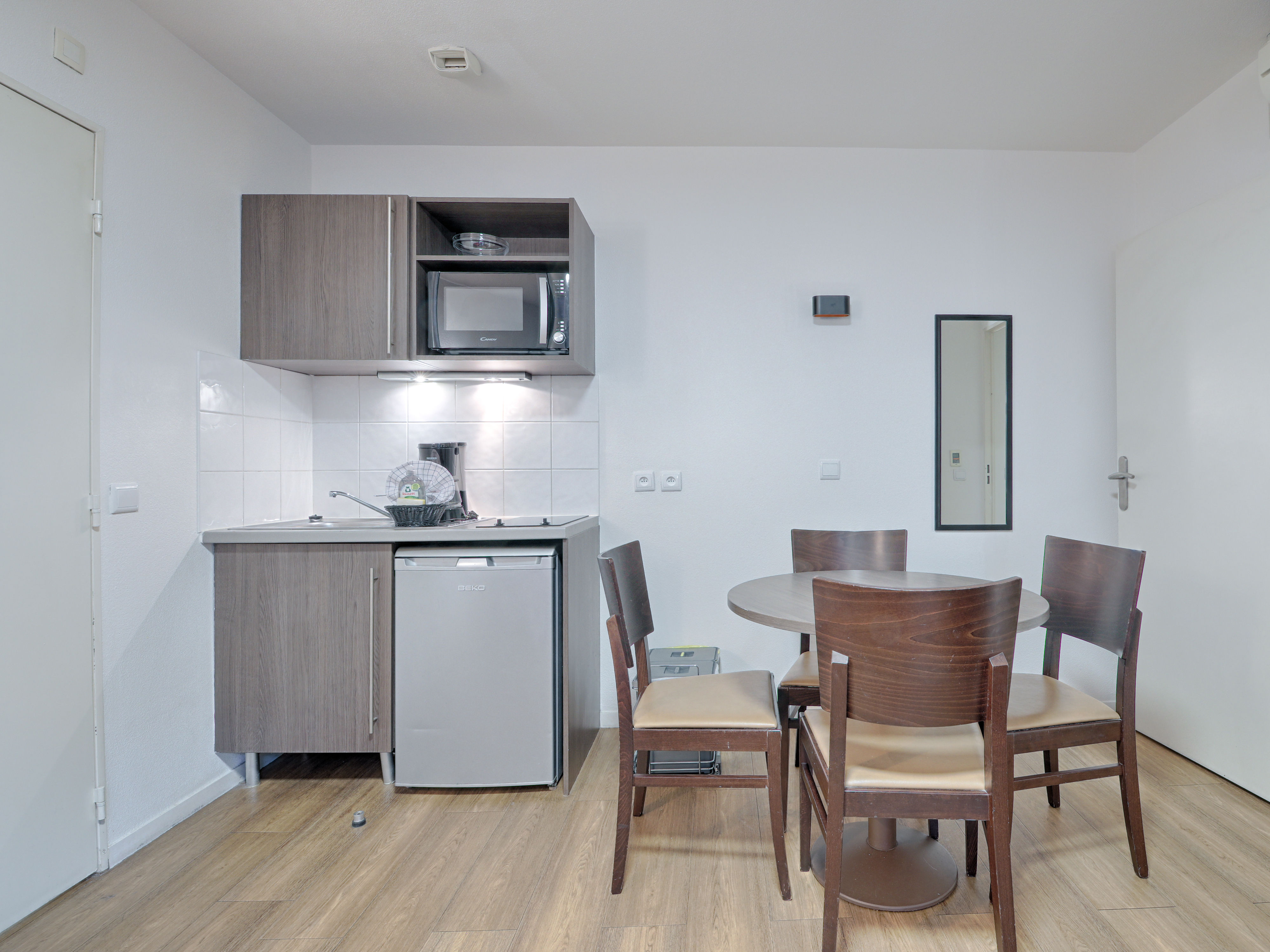 image Fully equipped kitchenette with modern appliances and a dining table for two, blending convenience and style.