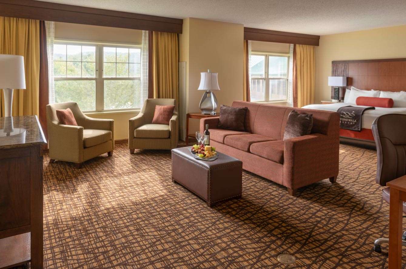 image Spacious suite with warm tones and lake-view windows invites you to unwind in quiet comfort.