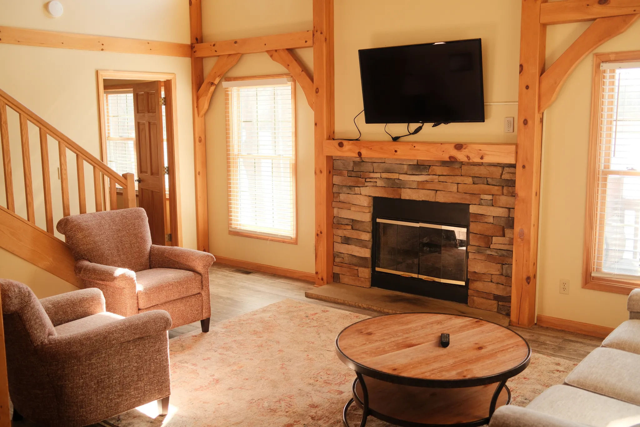 image Cozy up by the fire in this inviting living space framed by exposed beams and sunlit windows.