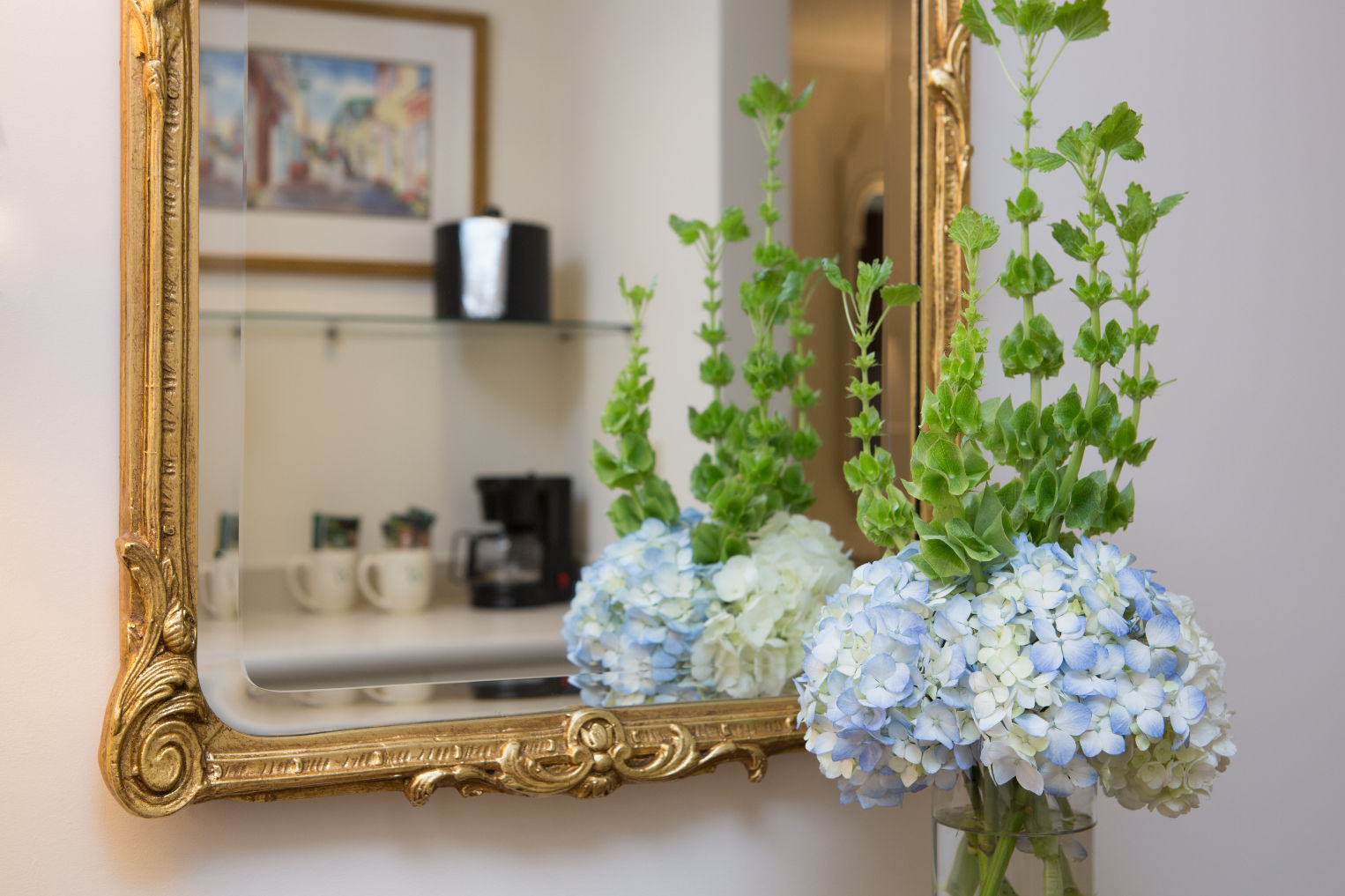 image Elegant floral arrangements and a classic gold-framed mirror add a touch of charm and sophistication.