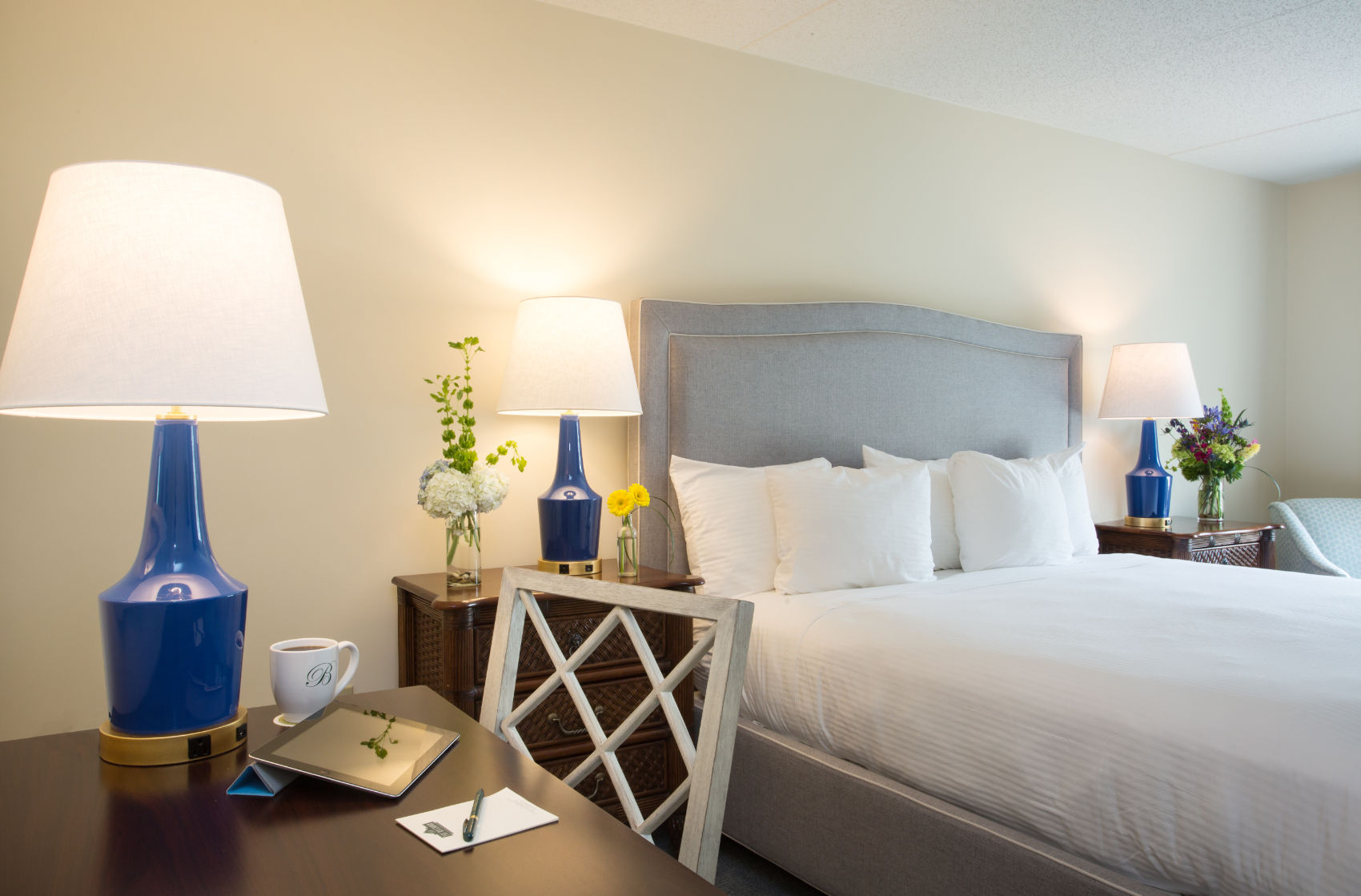 image A beautifully designed bedroom featuring elegant lighting, plush bedding, and a cozy workspace for ultimate comfort.