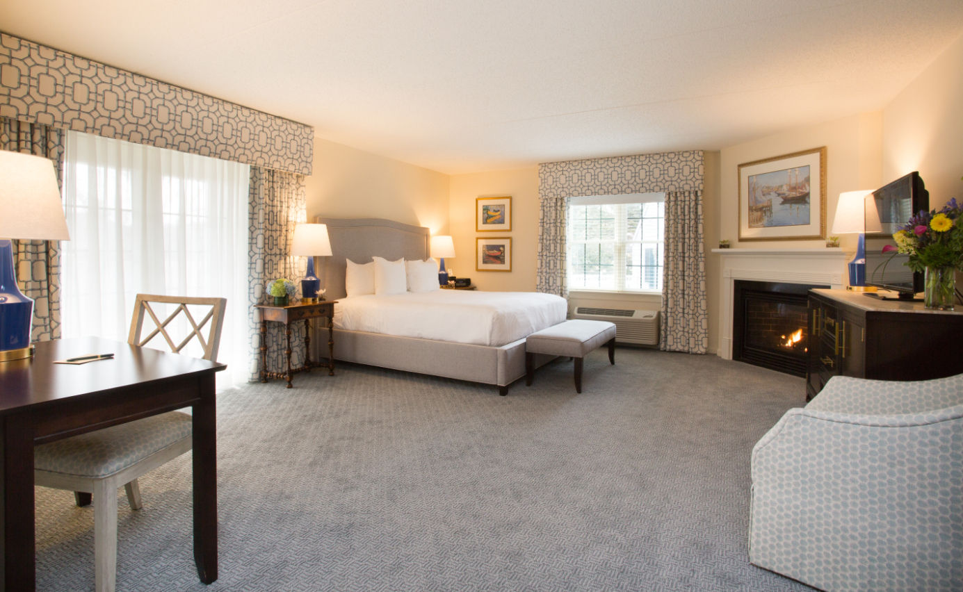 image Spacious and elegantly designed suite featuring a plush bed, comfortable seating, and a cozy fireplace.