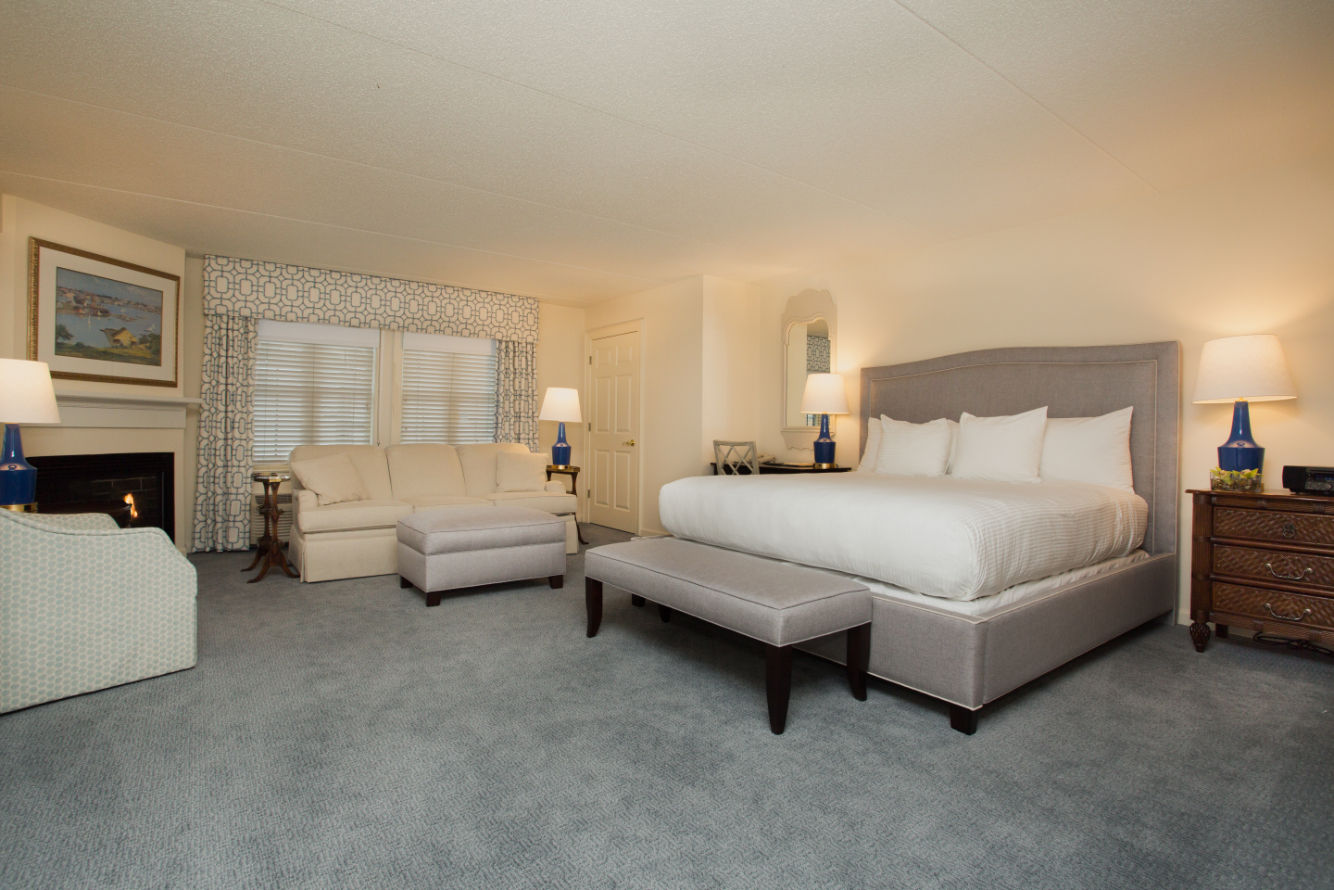 image Expansive suite featuring a plush bed, sophisticated furnishings, and a comfortable sitting area for ultimate relaxation.