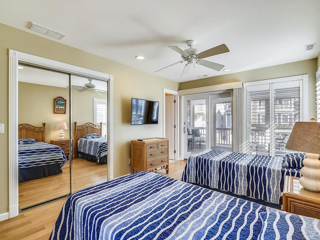 image This coastal-themed bedroom features two twin beds with ocean-inspired bedding and direct access to a private patio through sliding glass doors.
