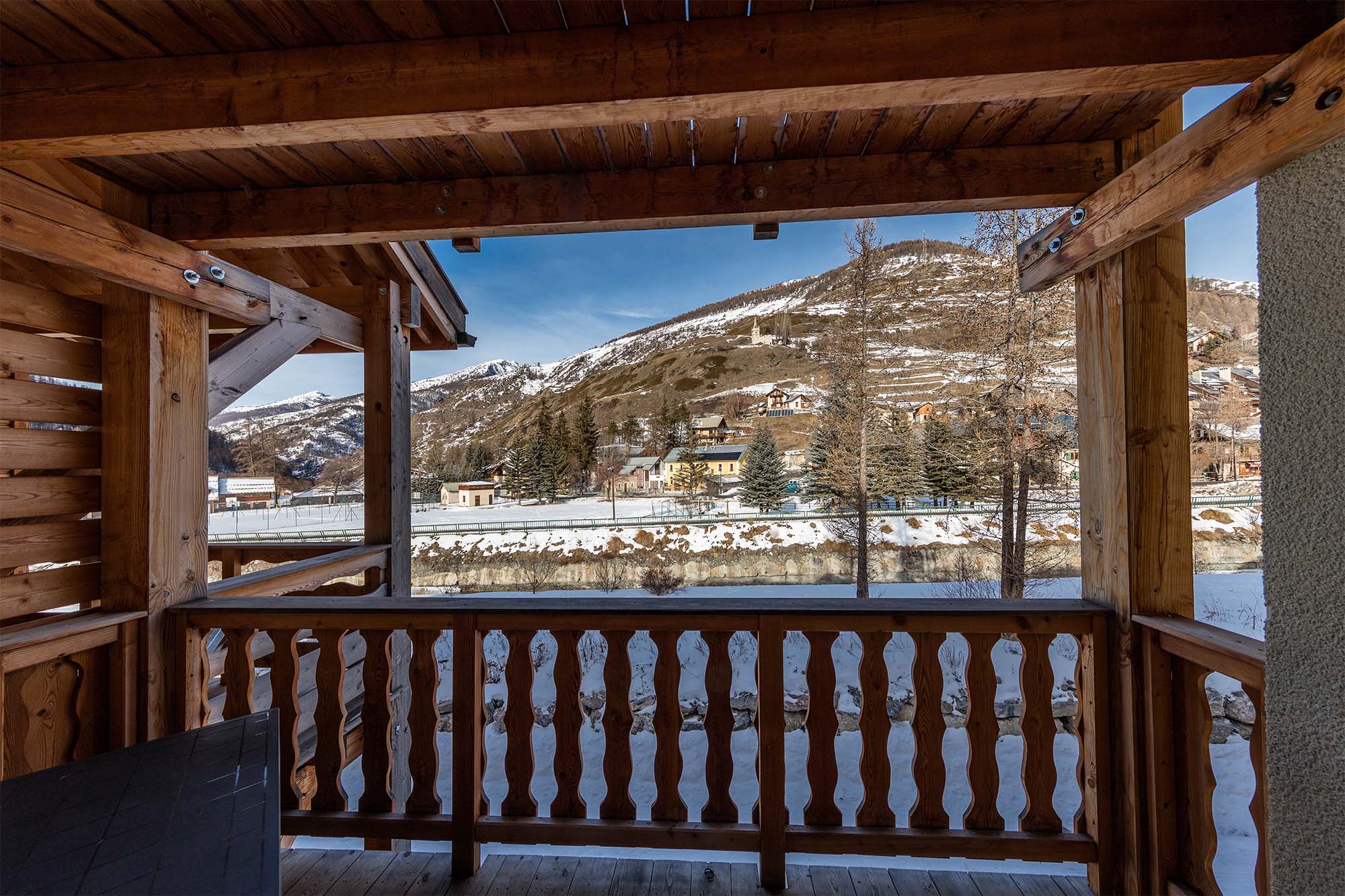 image A covered wooden balcony with stunning views of the surrounding snow-capped mountains.