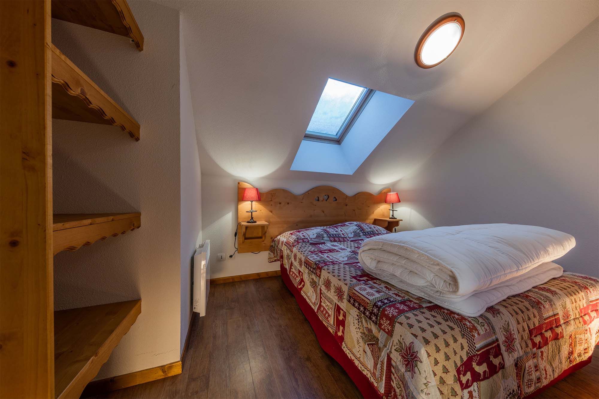 image Compact yet comfortable attic bedroom with soft lighting and a skylight for natural brightness.