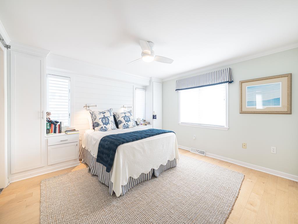 image This cozy bedroom is bathed in natural light, showcasing chic bedding, wooden flooring, and tasteful decor that invites relaxation and comfort.