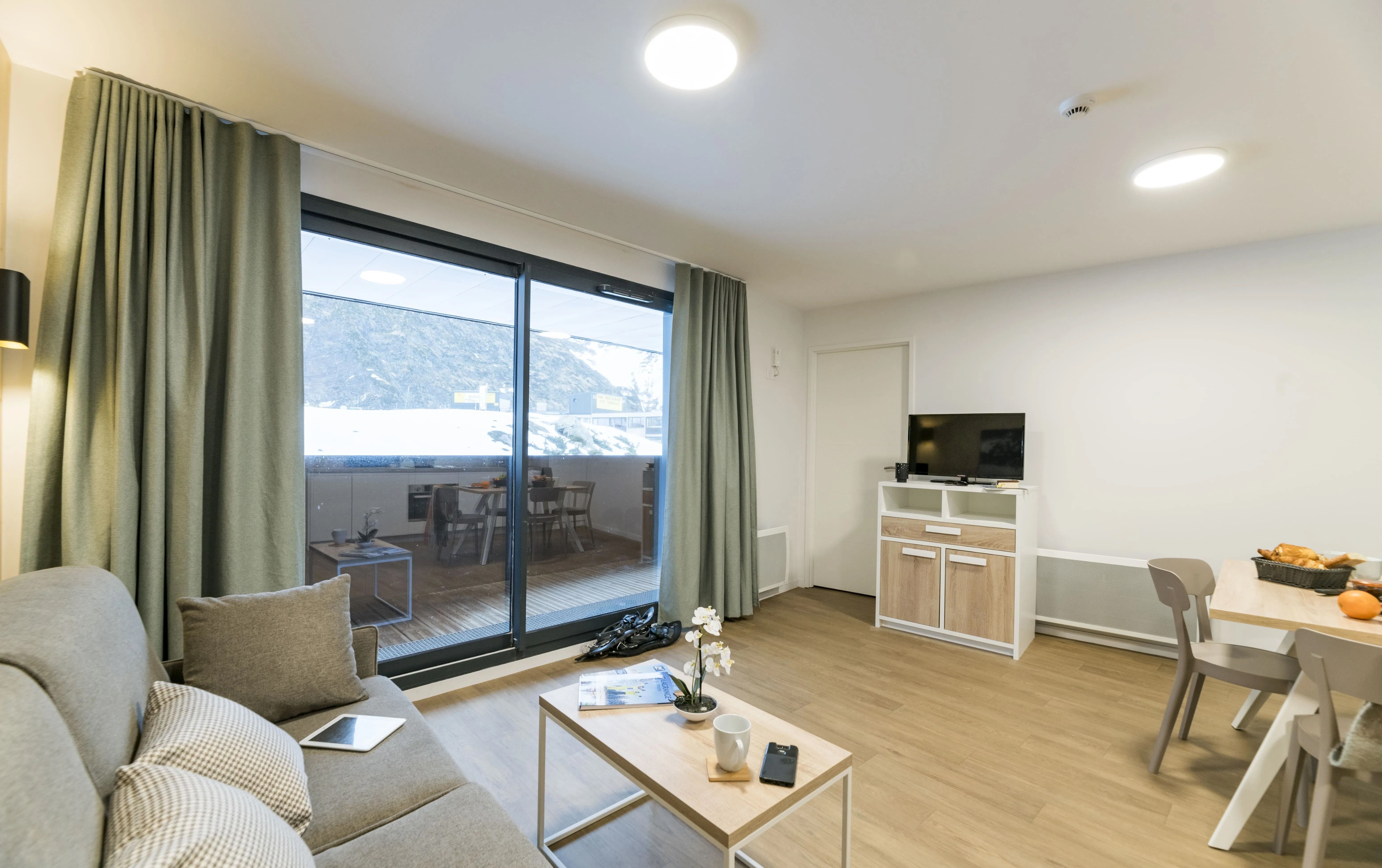 image Relax on the plush sofa while soaking in breathtaking mountain views, setting the perfect backdrop for your ski getaway in the French Alps.