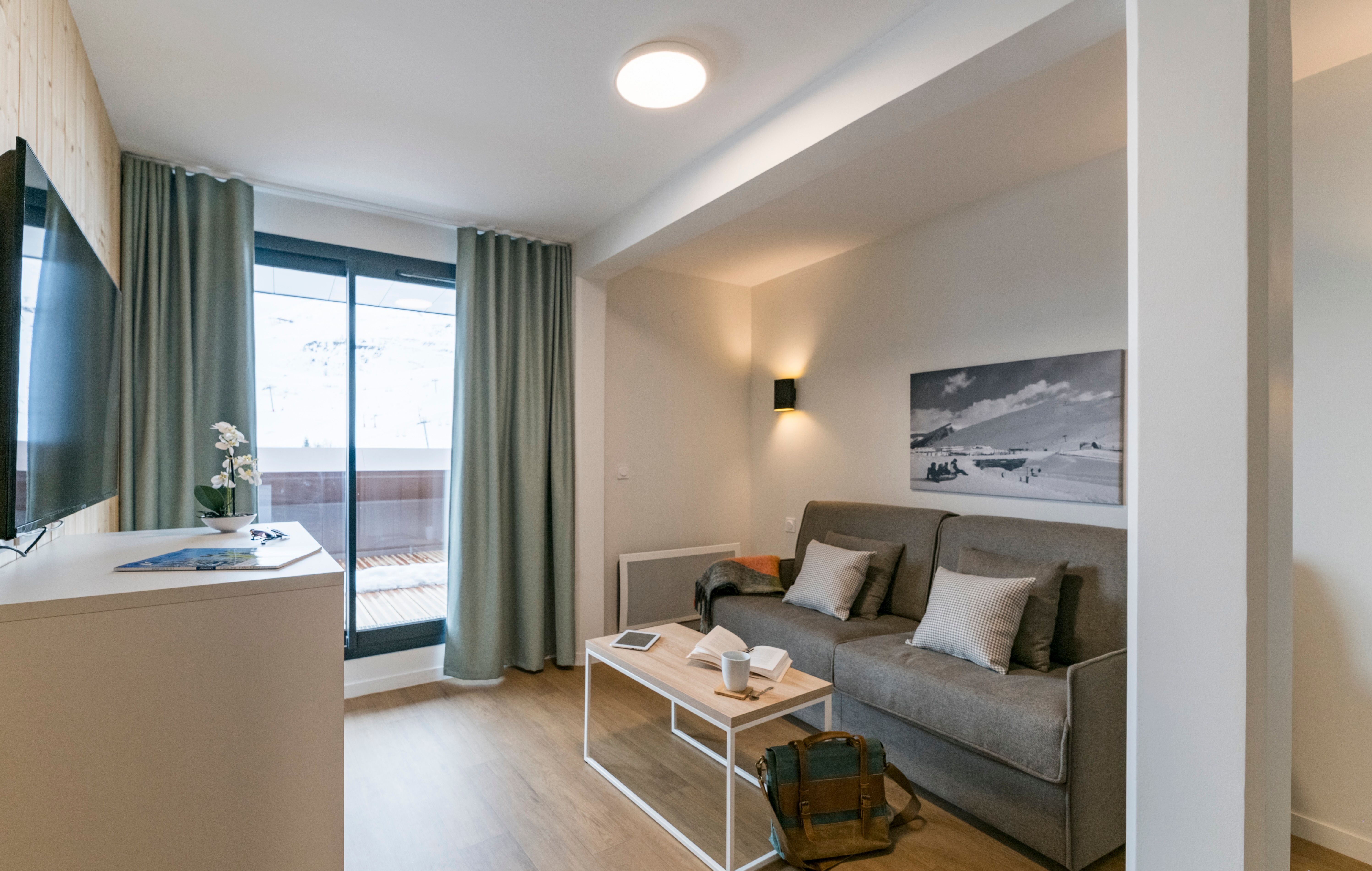 image Relax in this cozy living area featuring a comfortable sofa, beautiful artwork, and access to a private balcony, perfect for enjoying a cup of coffee in the morning light.