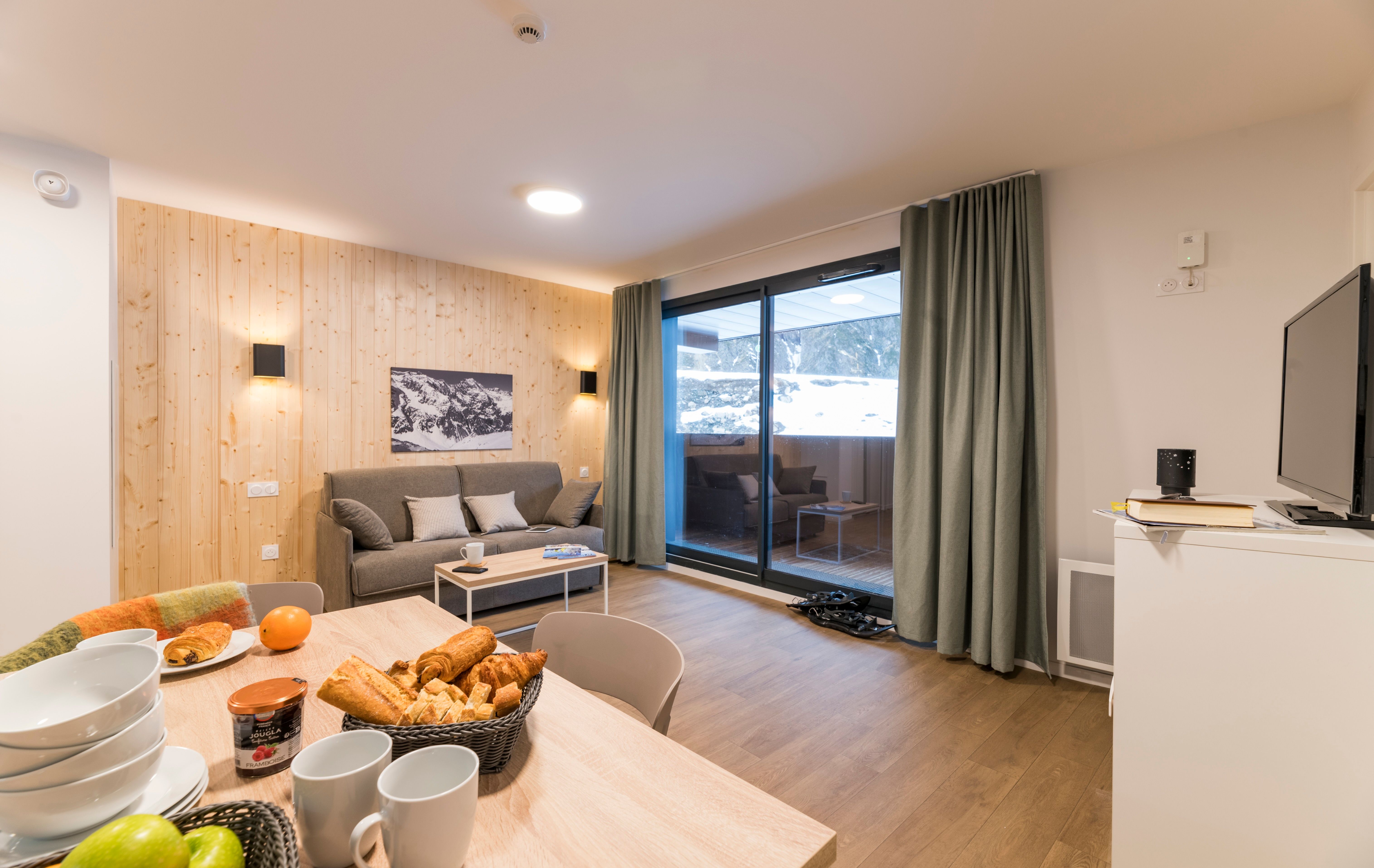 image Step into warmth and comfort in this inviting living area, perfect for family gatherings, featuring a cozy sofa and a beautiful view of snowy mountain peaks.