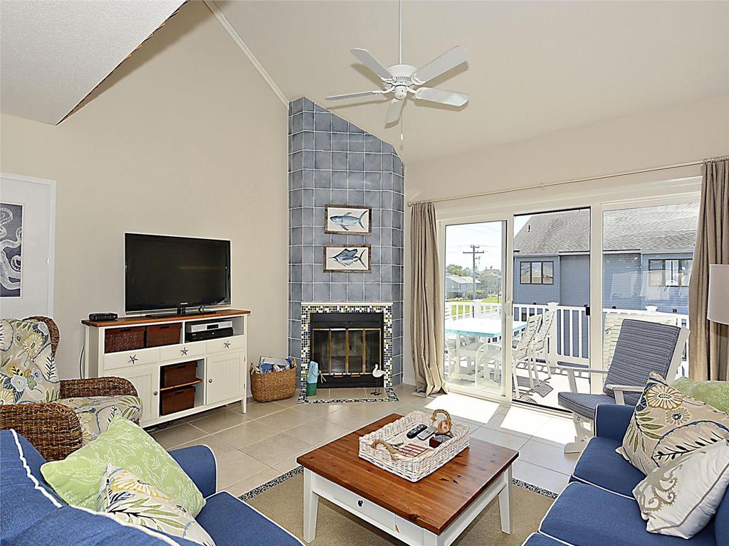 image Cozy living room with vaulted ceilings, a fireplace, and large windows that bring in plenty of natural light.