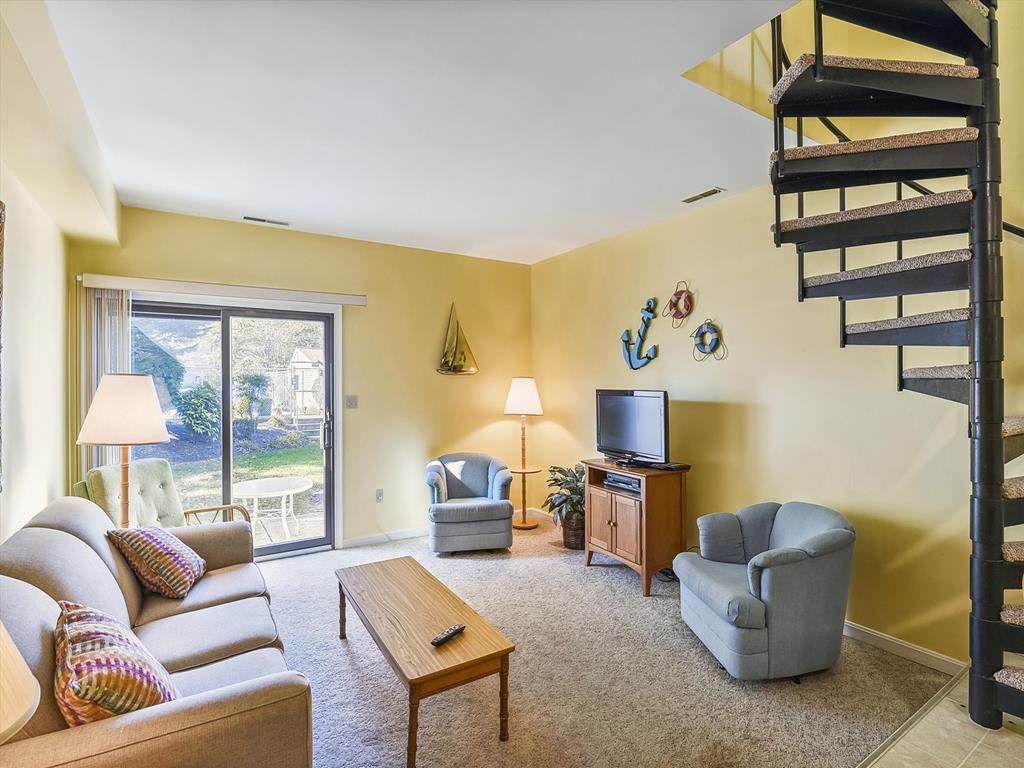 image Relax in the cozy living room adorned with coastal decor, complete with plush seating and large windows offering serene views of the outdoors.