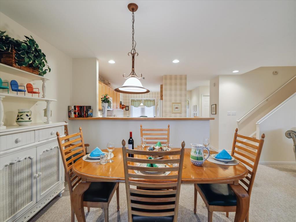 image The open-concept dining area showcases coastal-inspired decor, complemented by a well-lit ambiance and a view into the full kitchen, ideal for gatherings.