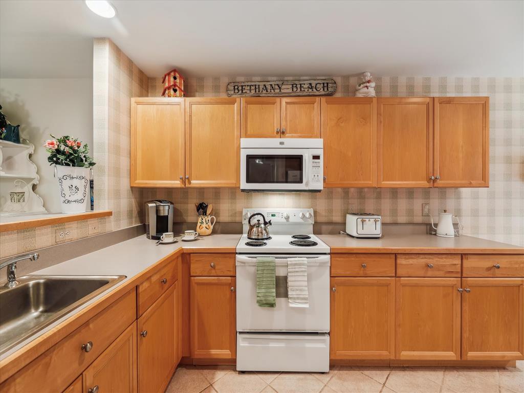 image Discover a bright and inviting full kitchen featuring wooden cabinetry, modern appliances, and a cozy coastal charm perfect for culinary adventures in the Sea Colony West townhome.