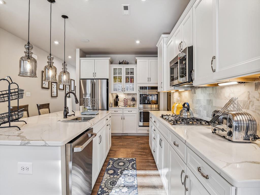 image The gourmet kitchen showcases high-end appliances and elegant countertops, creating an inviting space for culinary enthusiasts to thrive while enjoying views of the home’s bright interiors.