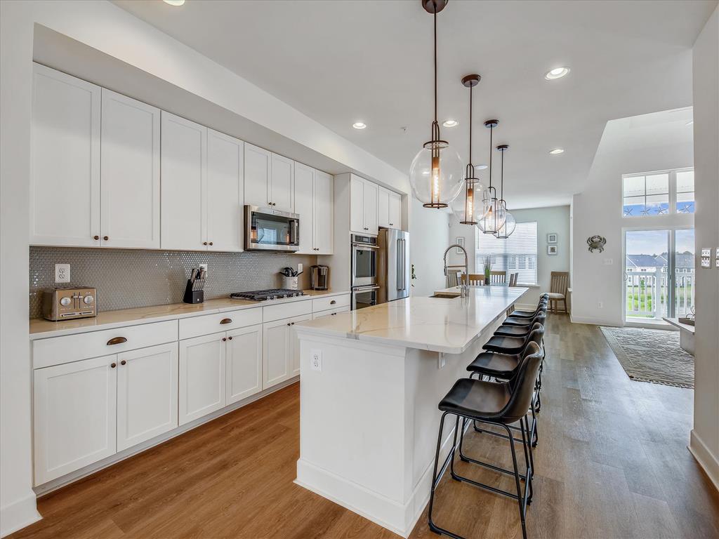 image Chef-inspired kitchen with an oversized island, sleek white cabinetry, and modern pendant lighting, perfect for preparing gourmet meals.