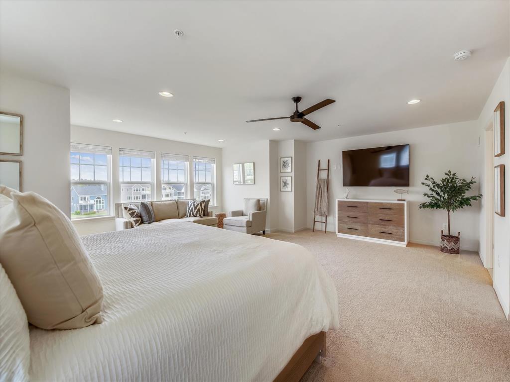 image Luxurious primary suite with a king-size bed, wall-mounted TV, and panoramic windows offering serene golf course views.