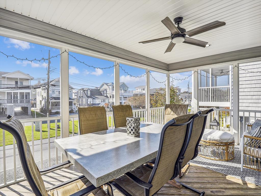 image Screened-in porch with ceiling fans and a dining area, perfect for enjoying meals with a view, rain or shine.