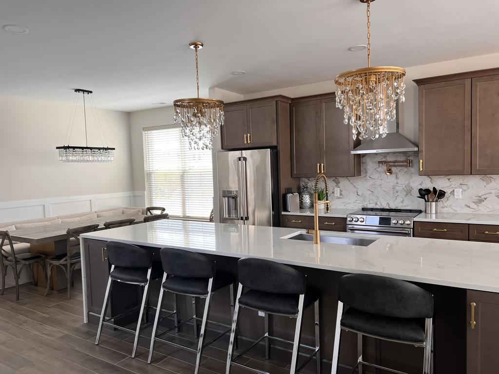 image A chef’s dream kitchen featuring a massive island, high-end appliances, and elegant chandeliers.