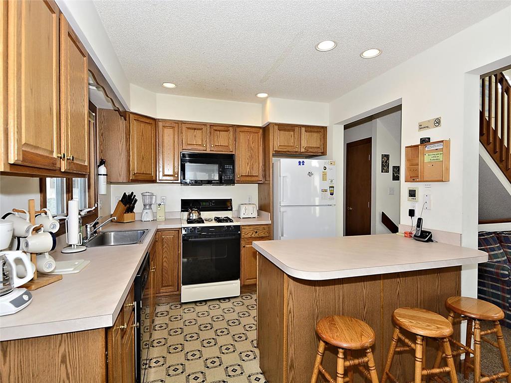 image Fully equipped kitchen featuring wooden cabinetry, modern appliances, and a breakfast bar.