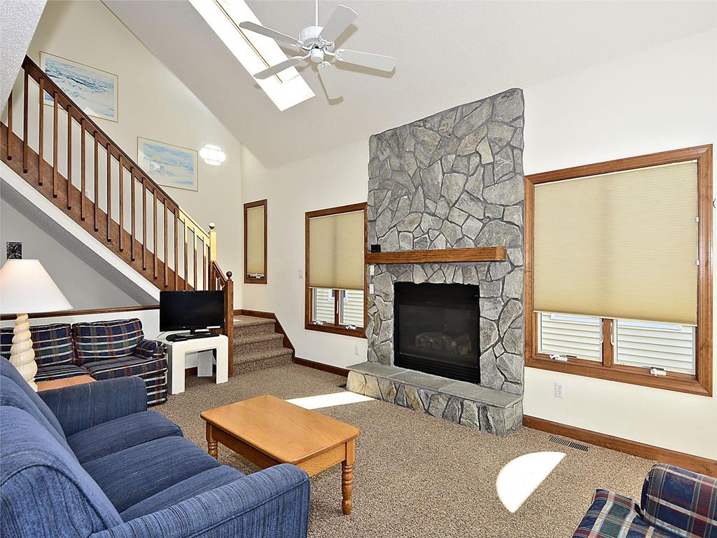 image Cozy living room with a stone fireplace, vaulted ceilings, and plenty of natural light.