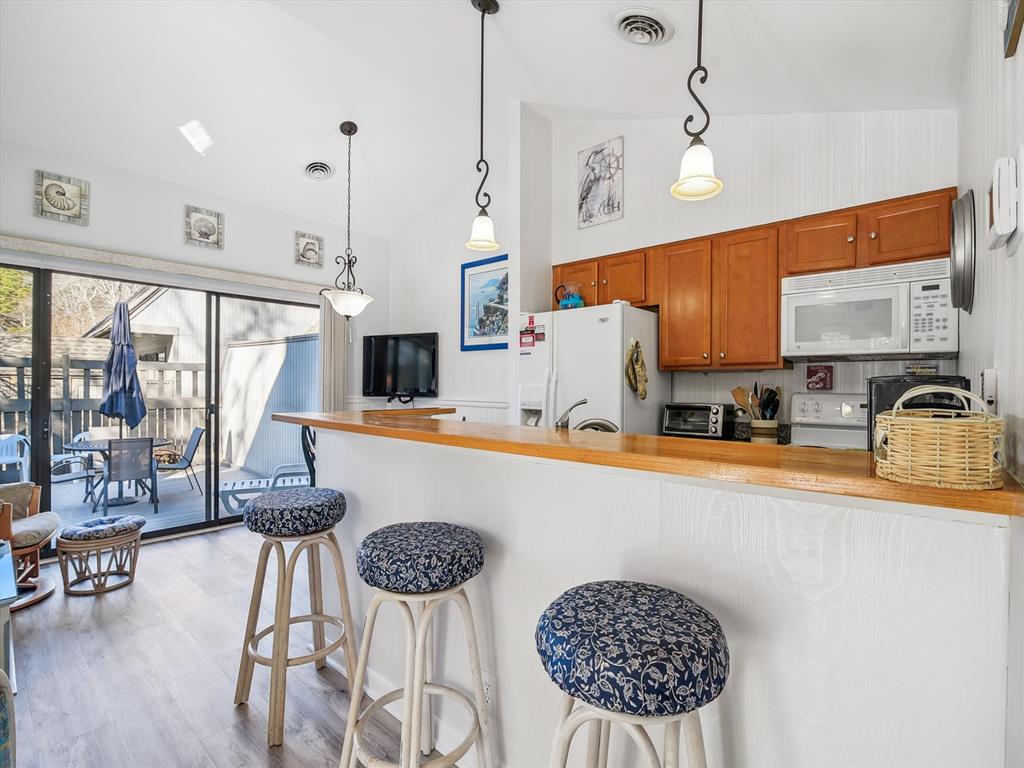 image Inside, the inviting kitchen features warm wooden cabinetry, a breakfast bar with stylish stools, and seamless access to the adjoining deck, perfect for entertaining.