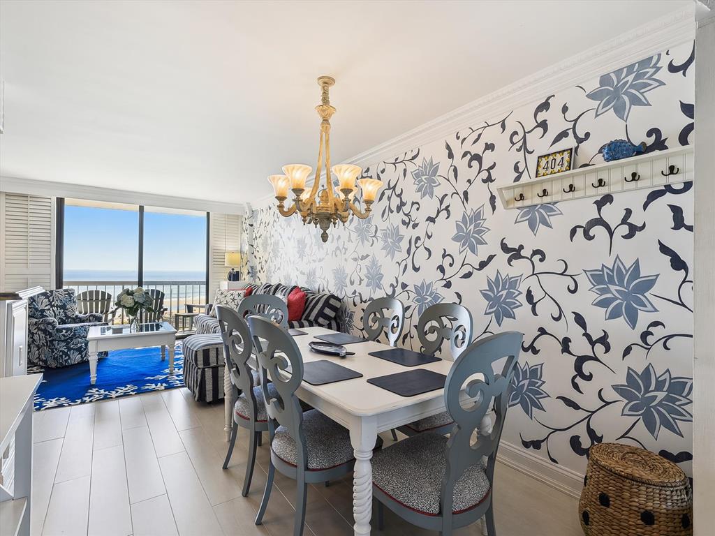 image Elegant ocean-view dining area with whimsical wall art and chandelier lighting.