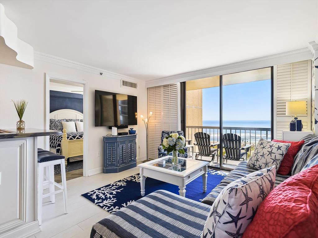 image In this beautifully arranged living area, rich textures and striking patterns unite around a coffee table, where guests can relax and enjoy the mesmerizing backdrop of the ocean.
