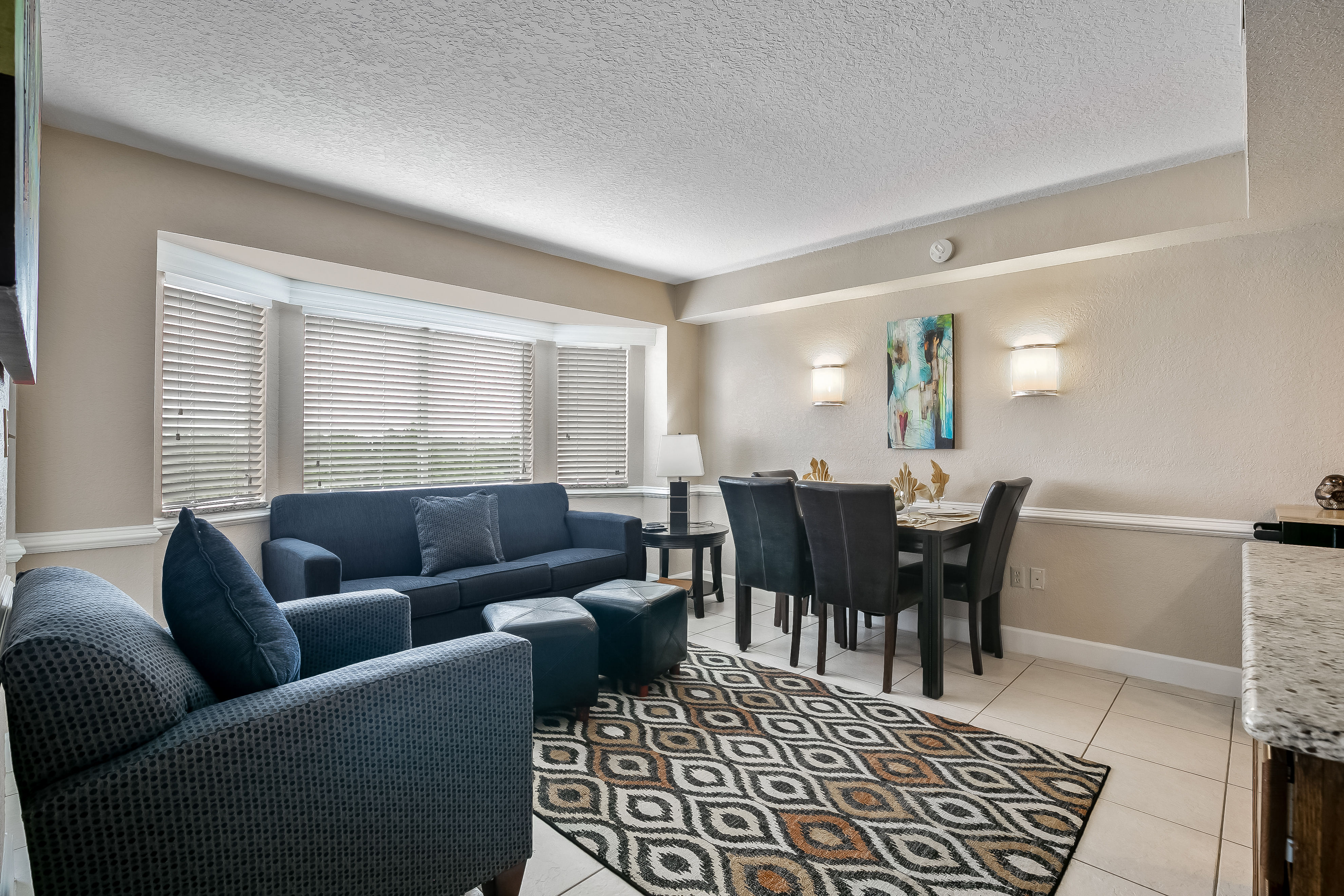 image The inviting living area showcases a plush sofa, a cozy dining space, and ample natural light through large windows, perfect for relaxation after a day at Disney World.