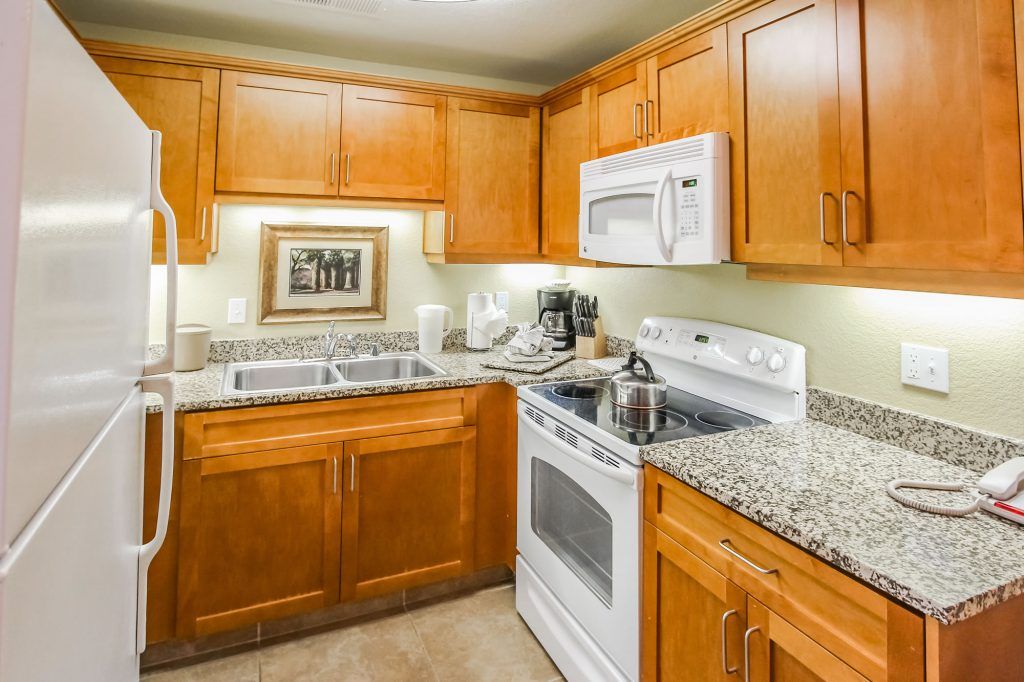 image Kitchen with wooden cabinets, double sink, stove, and microwave