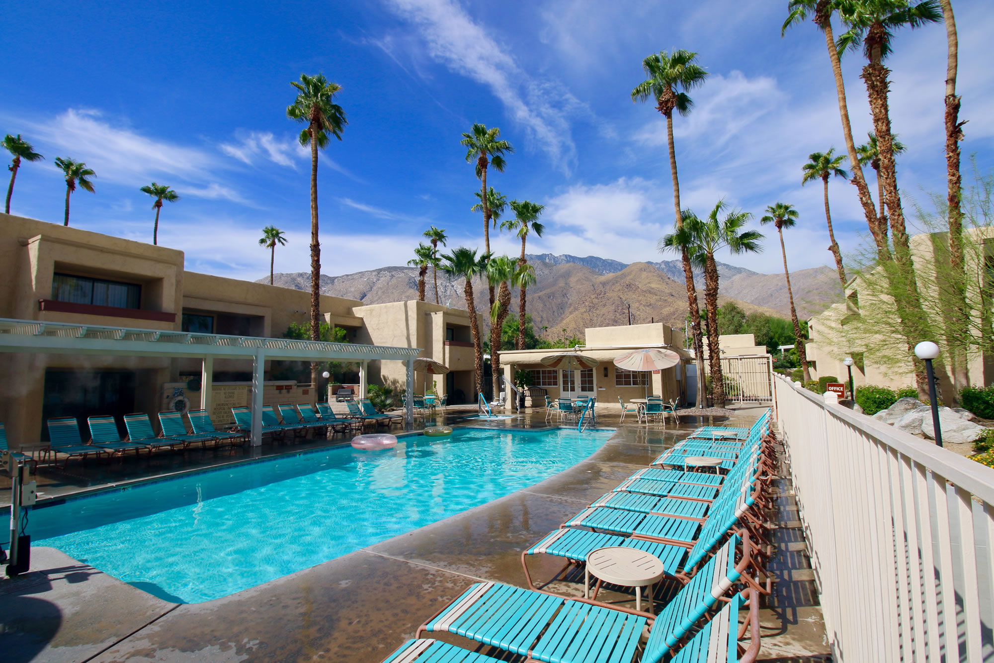 image Relax by the sparkling outdoor pool surrounded by palm trees and stunning mountain views, located just minutes from the Palm Springs Aerial Tramway in this spacious two-bedroom condo complex.