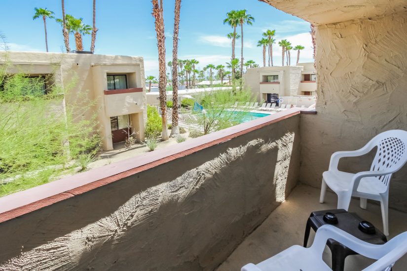 image Enjoy the fresh desert air from your private balcony, complete with seating, overlooking lush greenery and the inviting pool area.