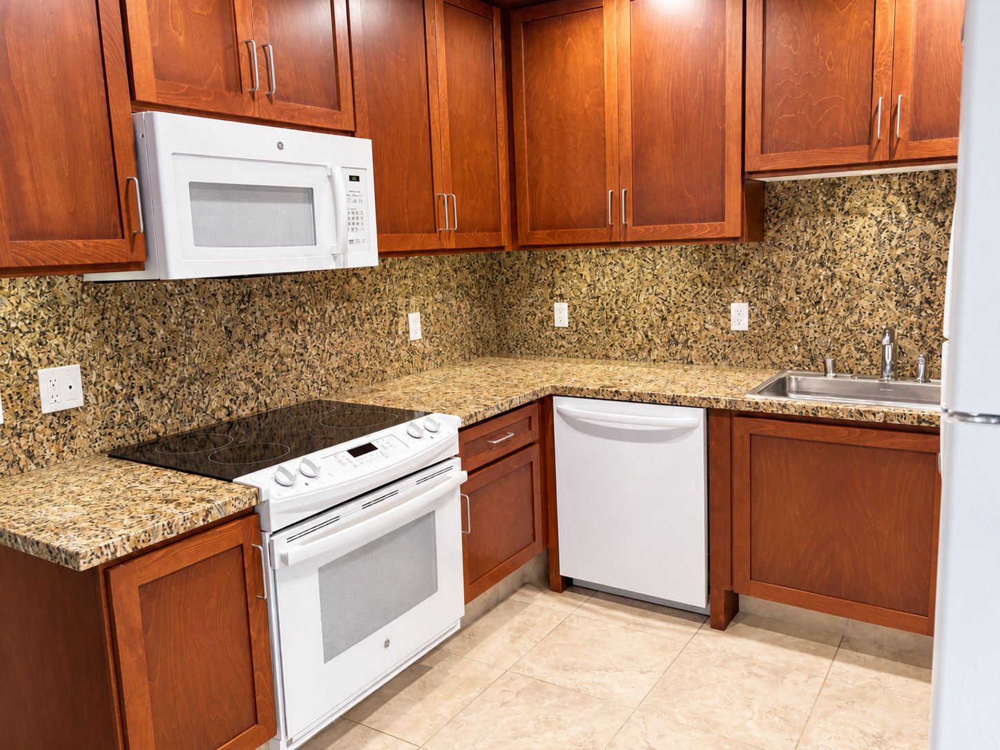 image Kitchen with wooden cabinets, stove, microwave, and sink
