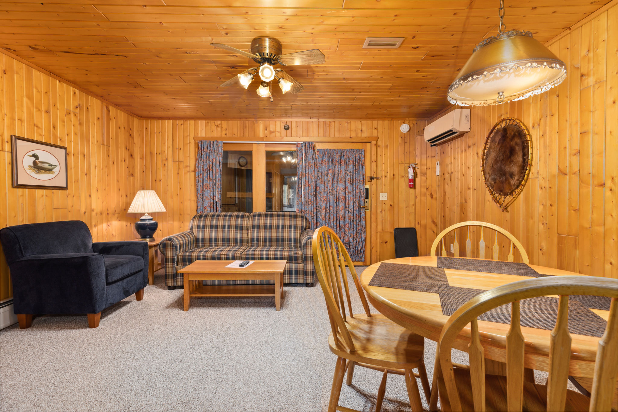 image The cozy living room, adorned with wooden walls and a plaid sofa, creates a warm atmosphere for relaxation and gatherings.