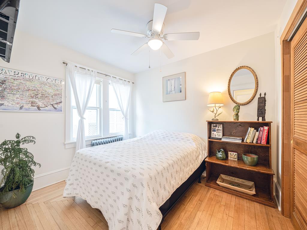 image This inviting bedroom offers a serene atmosphere with a ceiling fan, smart TV, and a beautifully organized bookshelf, ideal for family downtime.
