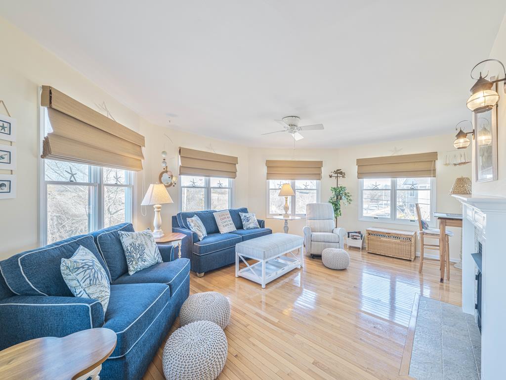 image Relax in the spacious living area adorned with coastal decor, featuring a plush blue sofa and abundant natural light from large windows, perfect for family gatherings after a sun-soaked day at the beach.