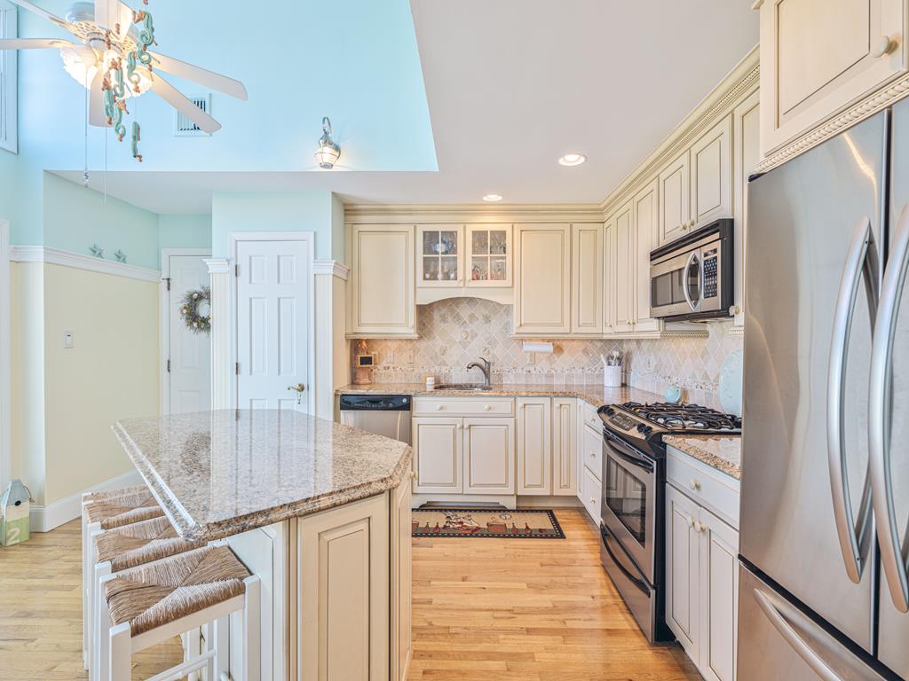 image Whip up family meals in this elegantly designed kitchen featuring ample counter space and modern appliances, set against a backdrop of sea greens and sandy hues reminiscent of the coast.