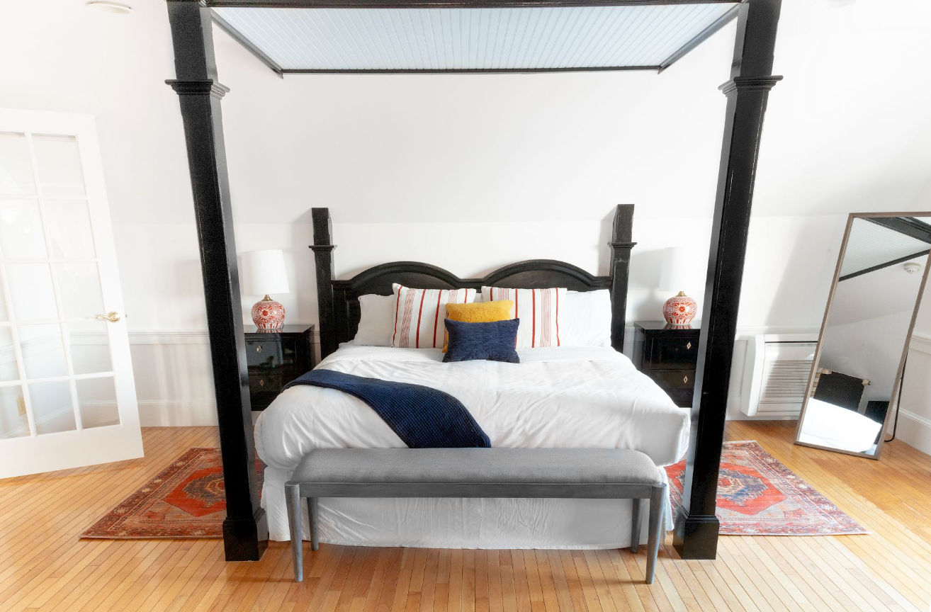 image Crisp linens and bold charm come together beneath towering posts, offering restful nights in a room full of character.