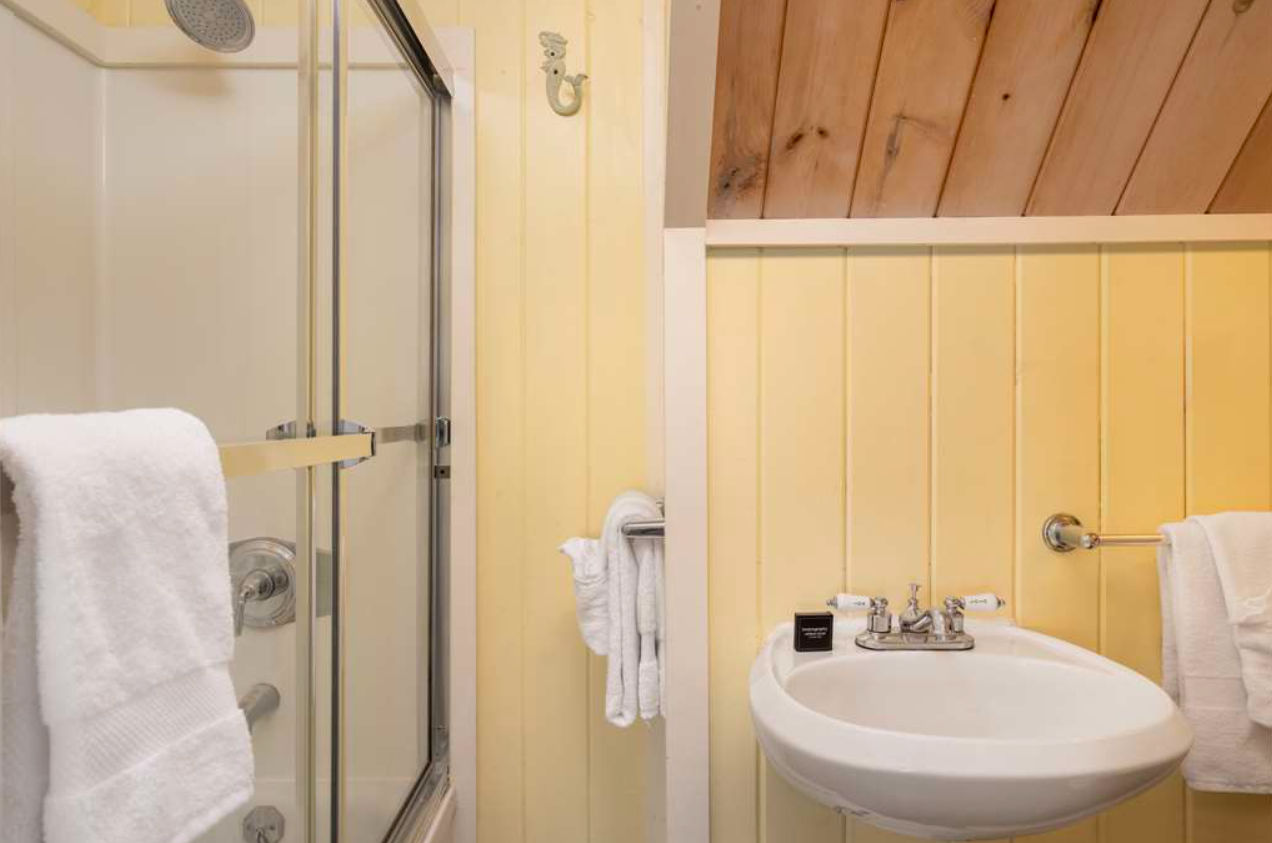 image Cheerful paneling and soft light bring coastal charm to this bright, refreshing bath tucked beneath a pitched ceiling.